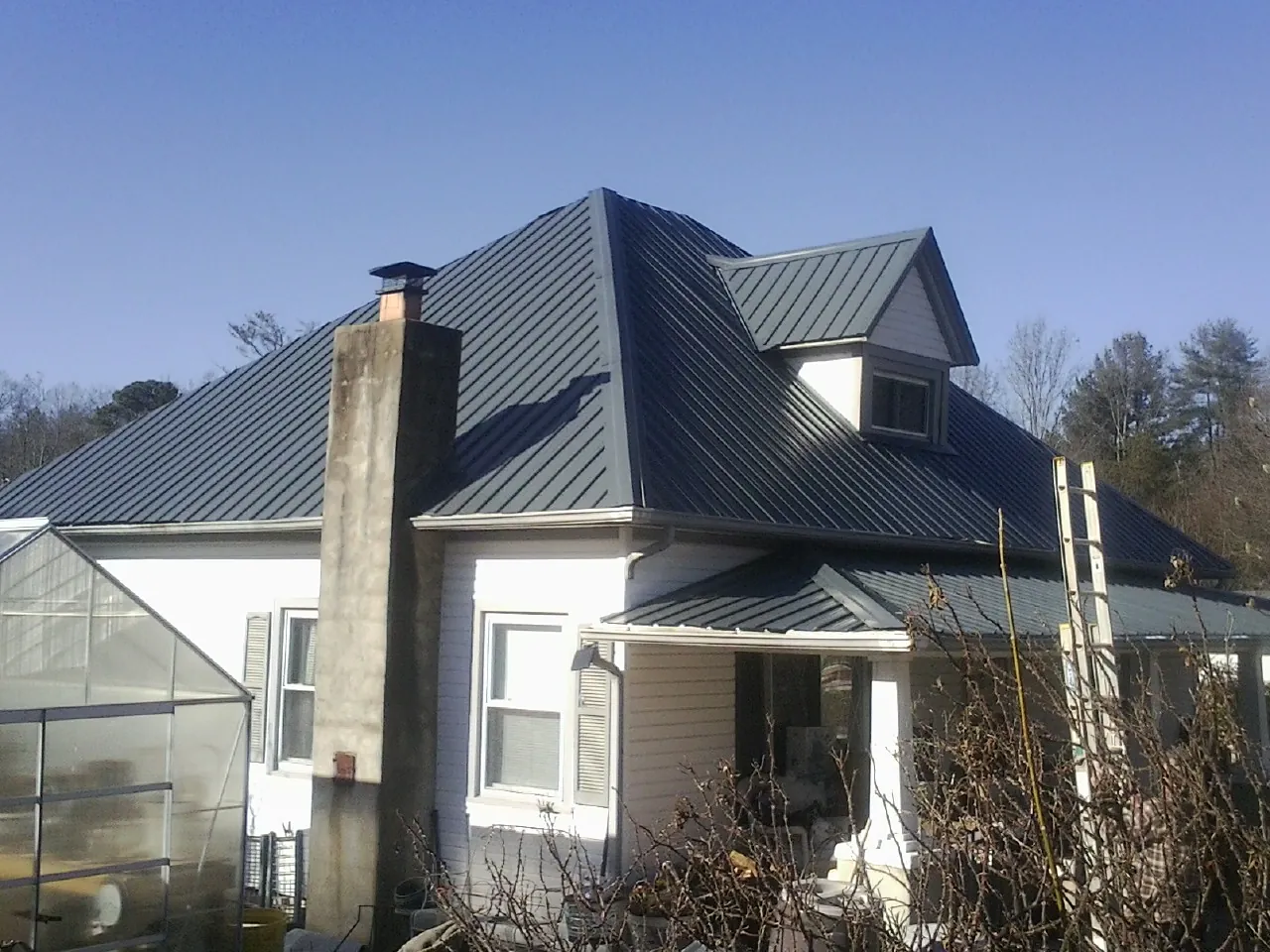 Dark blue standing seam metal roof on a white farmhouse with dormer — Slate & Tile Roof Repair by Roofing Brothers in Jersey Mills