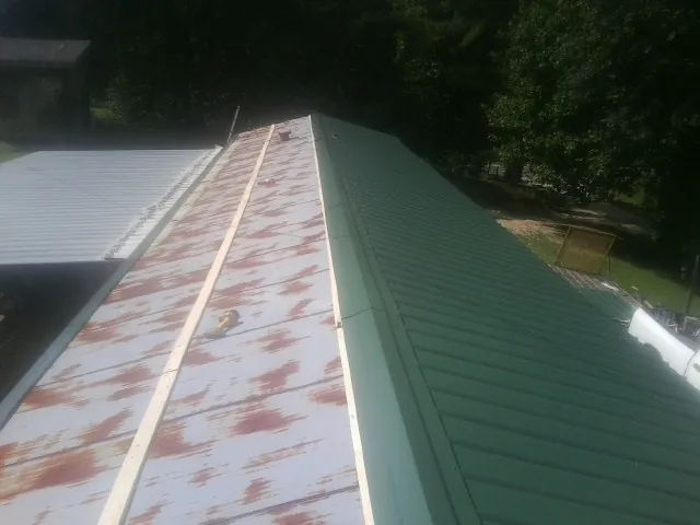 Old rusted panels beside newly installed green metal roofing — Wind Damage Roof Repair by Roofing Brothers in Jersey Mills