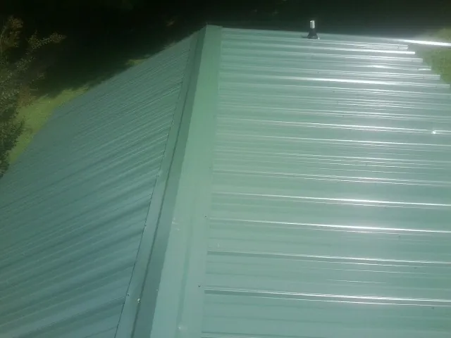 New green metal panels meeting at the ridge of a roof — Flat Roof Repair work by our crew in Jersey Mills