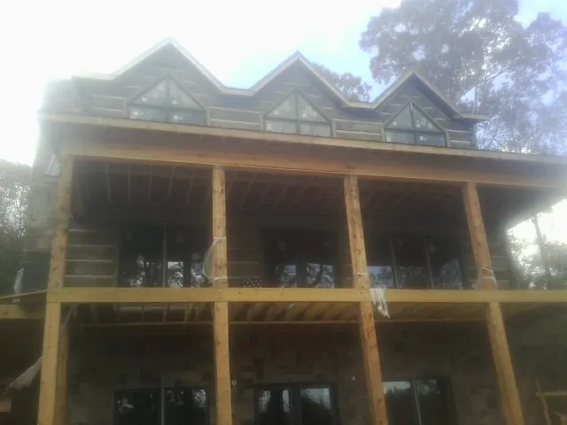 Dormers and porch framing on a large log home under construction — Roof Coating work by our crew in Jersey Mills