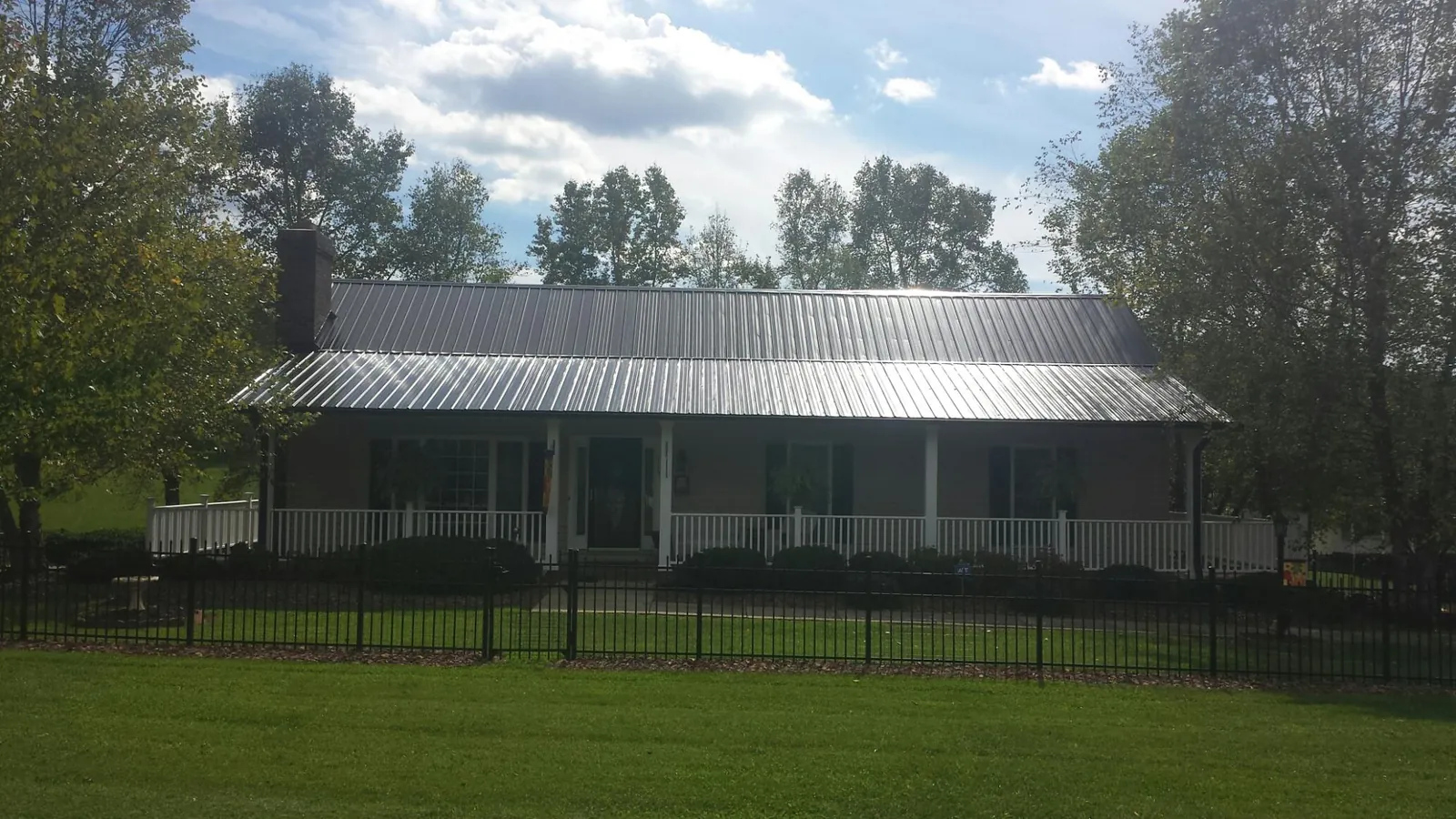 Gray metal roof on a brick ranch with a full width front porch — Gutter Guard Installation work by our crew in Jersey Mills