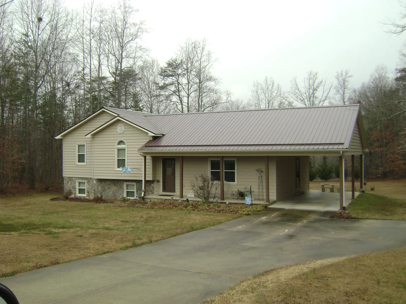Brown metal roof on a tan split level home with an attached carport in Jersey Mills