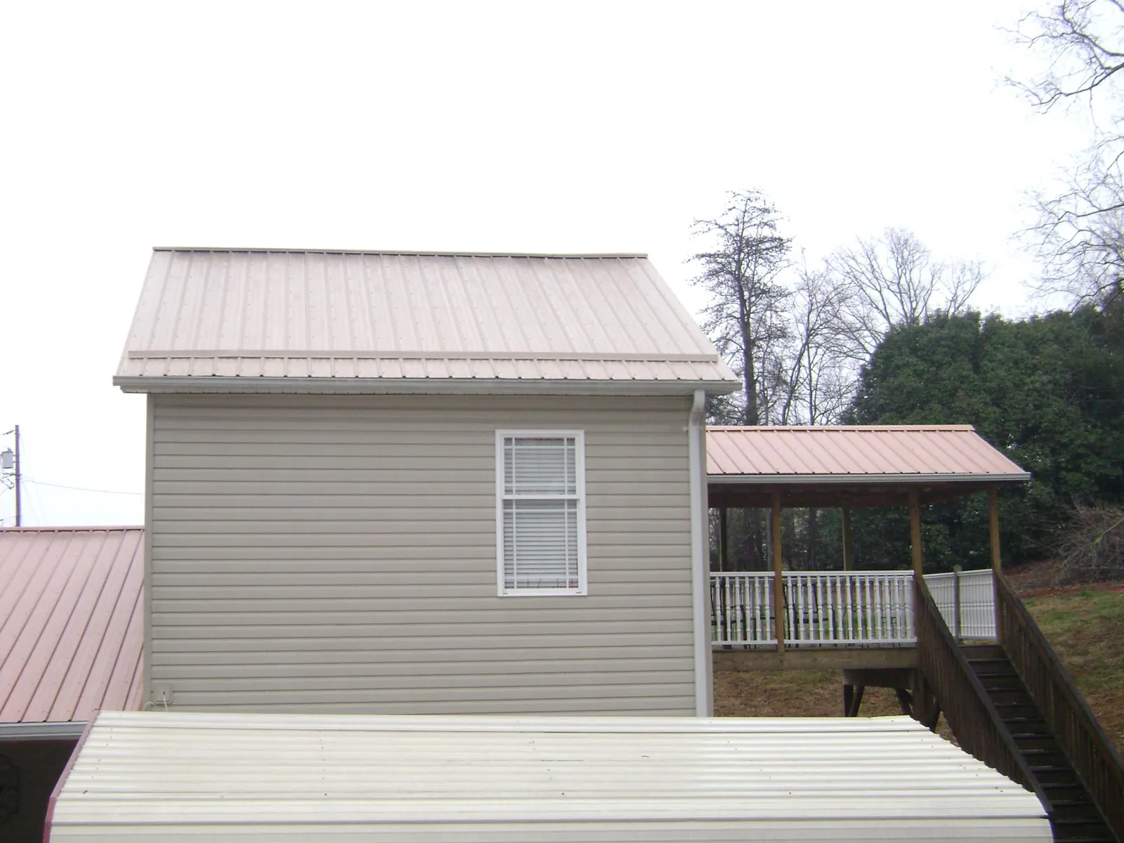Tan metal roofs on a two story addition and attached porch, from a Roof Replacement job in Jersey Mills