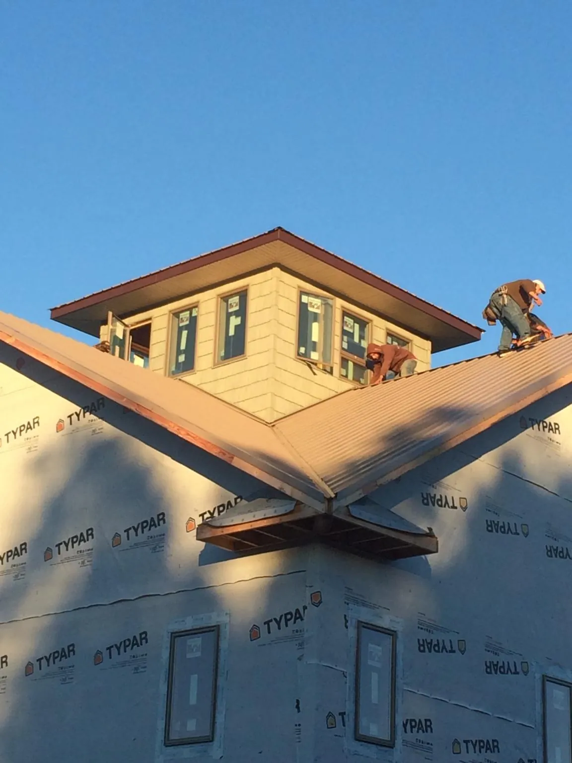 Roofers working around a rooftop cupola on a new metal roof at sunset — Roof Waterproofing in Jersey Mills by Roofing Brothers